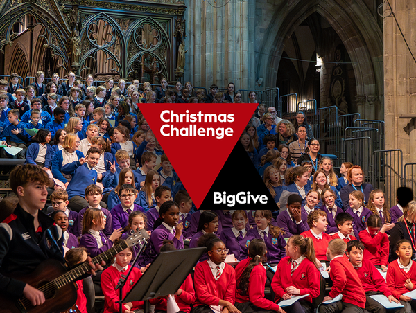 A photo of children singing at a showcase with the Big Give logo.