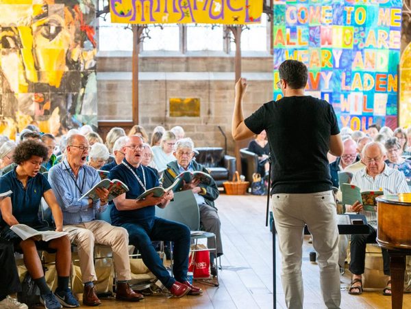 A Come and Sing event with people singing, and Neil Ferris conducting
