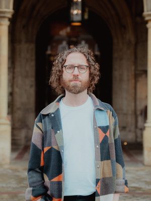 Gavin Higgins standing in front of Gloucester Cathedral's main entrance.
