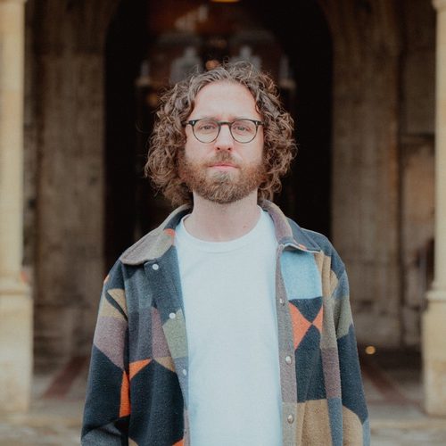 Gavin Higgins standing in front of Gloucester Cathedral's main entrance.