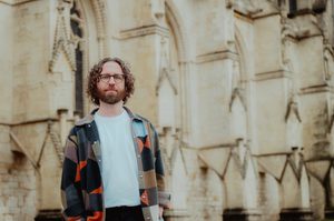 Gavin Higgins standing in front of Gloucester Cathedral