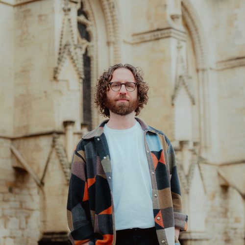 Gavin Higgins standing in front of Gloucester Cathedral
